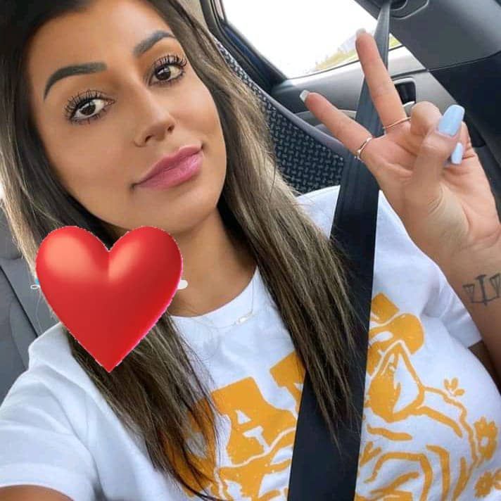 a woman sitting in a car holding up a red heart