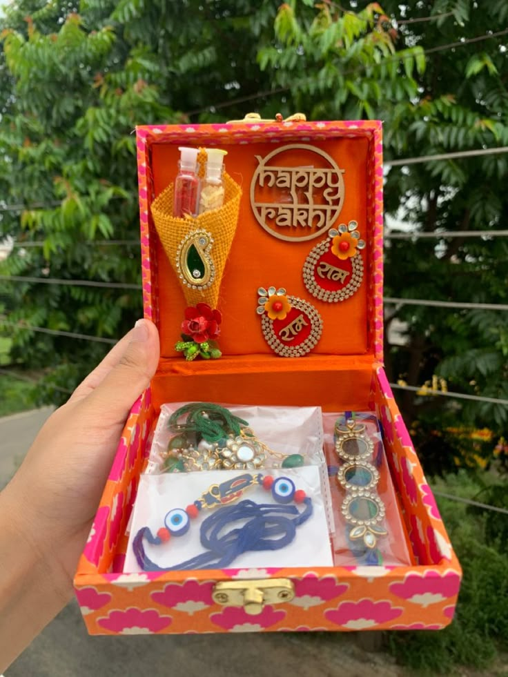 someone is holding an orange and pink box with jewelry in it that says happy diwal