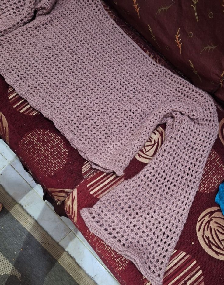 a crocheted sweater laying on top of a bed