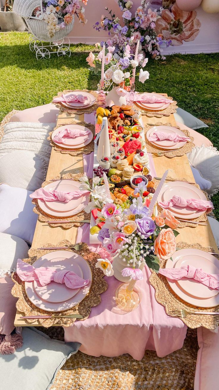 a table set up with pink and yellow plates, napkins and flowers on it