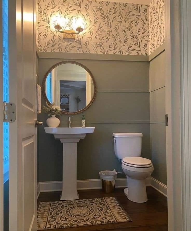 a white toilet sitting next to a bathroom sink under a mirror on top of a wooden floor