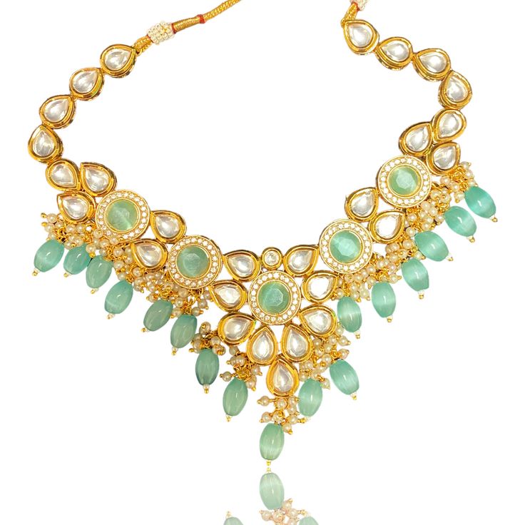 The Teal Aayra Kundan Neckline Set features a beautiful combination of high quality Kundan, American Diamond, Teal Beads and Pearls. Set comes with a necklace and a pair of earrings. The center of the necklace has a beautiful flower motif with teal monalisa beads in the center, surrounded by american diamonds. The flower petals are made of beautiful kundan. The back of the necklace and earrings have hand painted meenakari which gives a smooth fit. Specifications Materials used: kundan, teal mona Bollywood Style Festive Necklace With Dangling Beads, Bollywood Style Festive Necklaces With Dangling Beads, Bohemian Green Bridal Necklace For Wedding, Beaded Necklaces For Receptions And Festivals, Festive Beaded Necklace For Reception, Festive Bollywood Necklace With Dangling Beads, Bollywood Style Beaded Necklaces For Reception, Bohemian Wedding Beaded Necklaces With Stone Work, Bollywood Kundan Necklace With Dangling Beads For Wedding