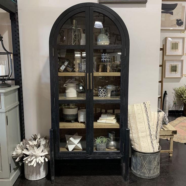 a black china cabinet with glass doors and shelves