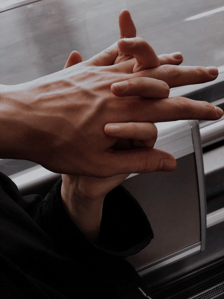 two hands reaching towards each other in front of a window