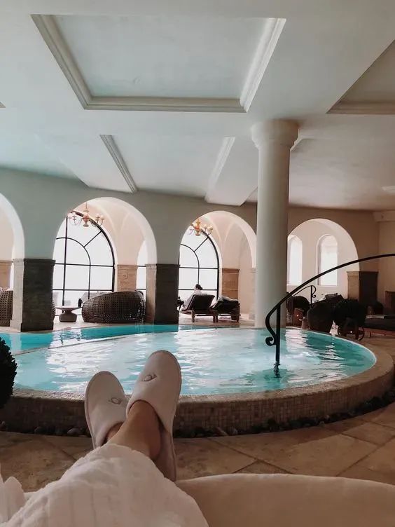 a person laying in front of a swimming pool with their feet up on the edge