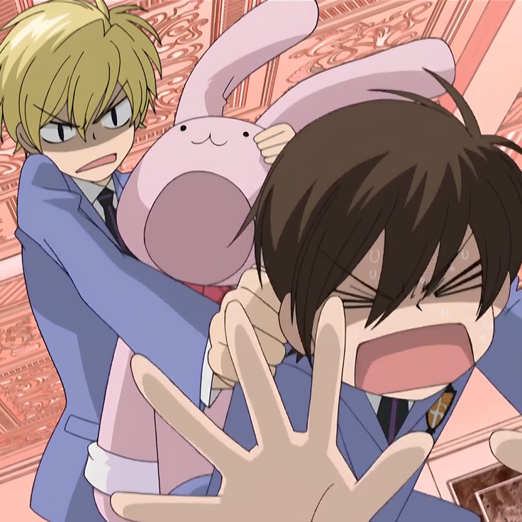 two anime characters are hugging each other in front of a pink wall with an animal on it