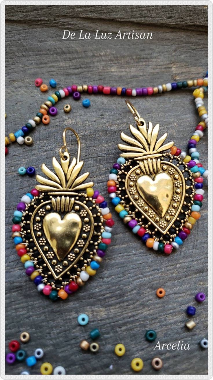 Arcelia Earrings Materials:  10k Gold plated hooks,  Sterling Silver plated hooks, Silver plated heart, brass wire, glass beads Length:  2.5" Available in silver or gold milagro flaming hearts, the Arcelia earrings are inspired by Mexican Folk Art & the colorful embroidery crafted throughout Latin America.  I wrapped a vibrant blend of Fiesta inspired colors around these gorgeous hearts.   The gold set has 10k gold hooks & the silver set has sterling silver hooks The sacred heart is a symbol of everlasting love & commitment. Your earrings will be very similar to the ones shown, but due to natural variation your set will be uniquely one of a kind. I gladly accept custom work.  If you are interested in a custom bead color around the Arcelia Earrings please message me to get started.   All or Multicolor Heart-shaped Jewelry For Wedding, Heart-shaped Multicolor Jewelry For Wedding, Heart-shaped Pierced Earrings For Festivals, Multicolor Heart-shaped Pierced Jewelry, Multicolor Heart Charm Drop Earrings, Multicolor Heart Charm Dangle Earrings, Multicolor Beaded Earrings For Wedding, Gold Heart Beads Jewelry For Festival, Gold Heart-shaped Earrings For Festivals