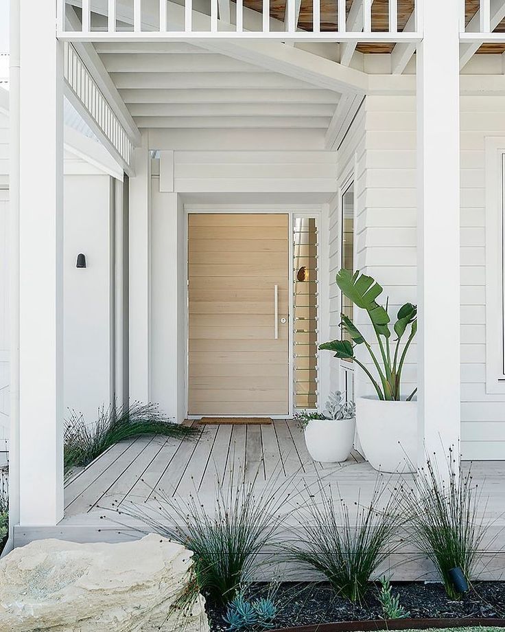 a white house with two large planters on the front porch and one door open