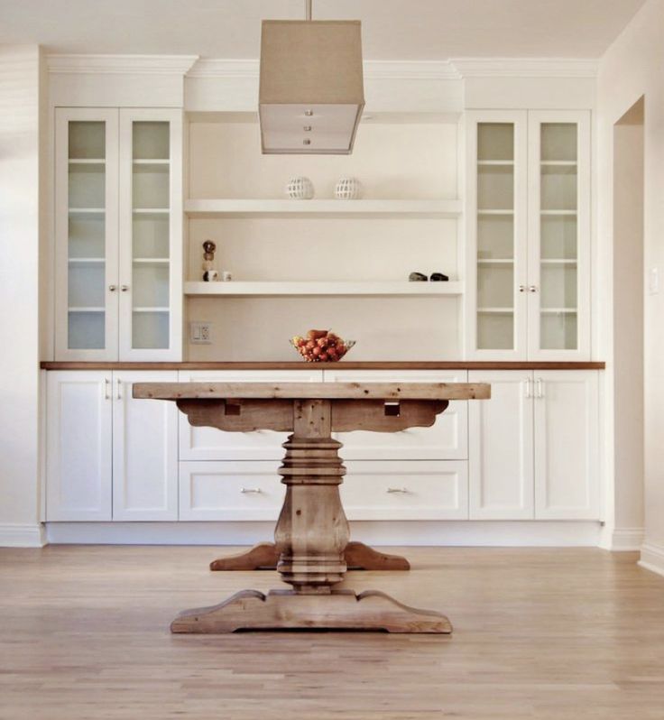 a kitchen with white cabinets and an island table in front of the stove top oven