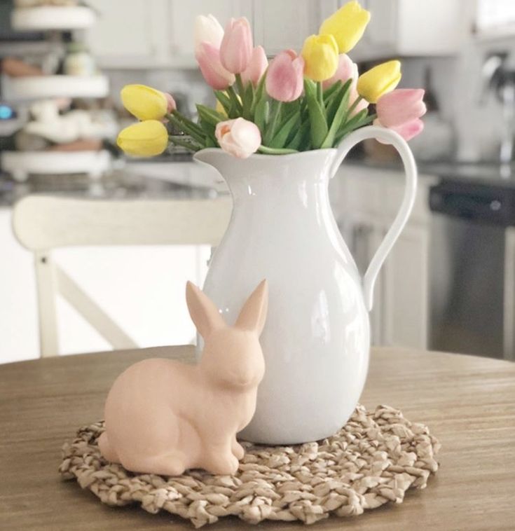 a white vase filled with yellow and pink tulips on top of a table