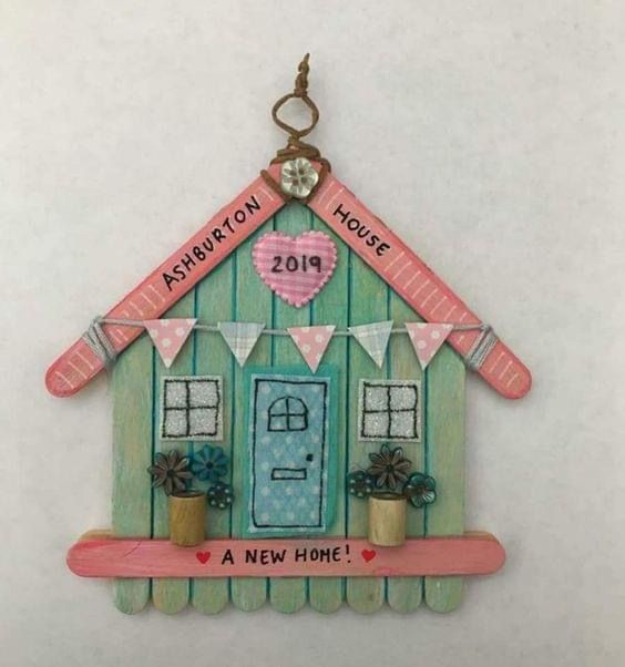 a house shaped ornament with a heart hanging from it's side