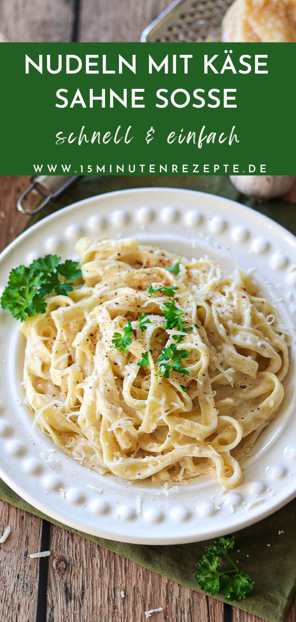 a white plate topped with pasta and parsley on top of a wooden table next to bread