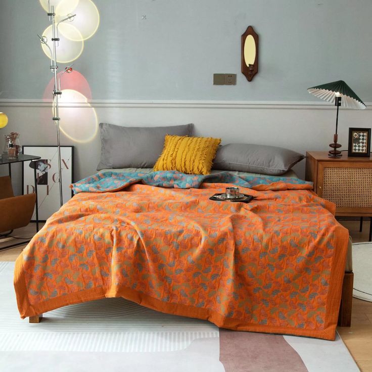 a bed with an orange comforter on top of it in a room filled with furniture