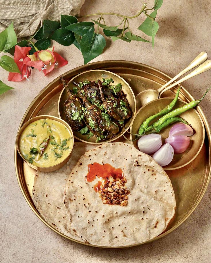 an assortment of food on a plate with chopsticks and flowers in the background