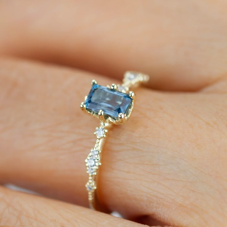 a woman's hand with a ring on it that has an aqua blue stone in the center