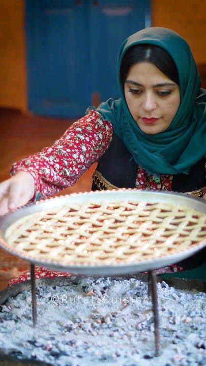 a woman wearing a headscarf is making pies