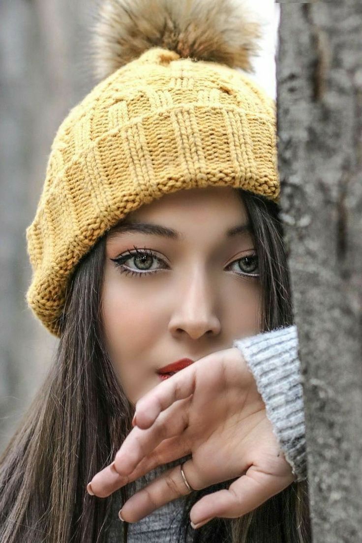 a young woman wearing a yellow hat with a pom - pom on it