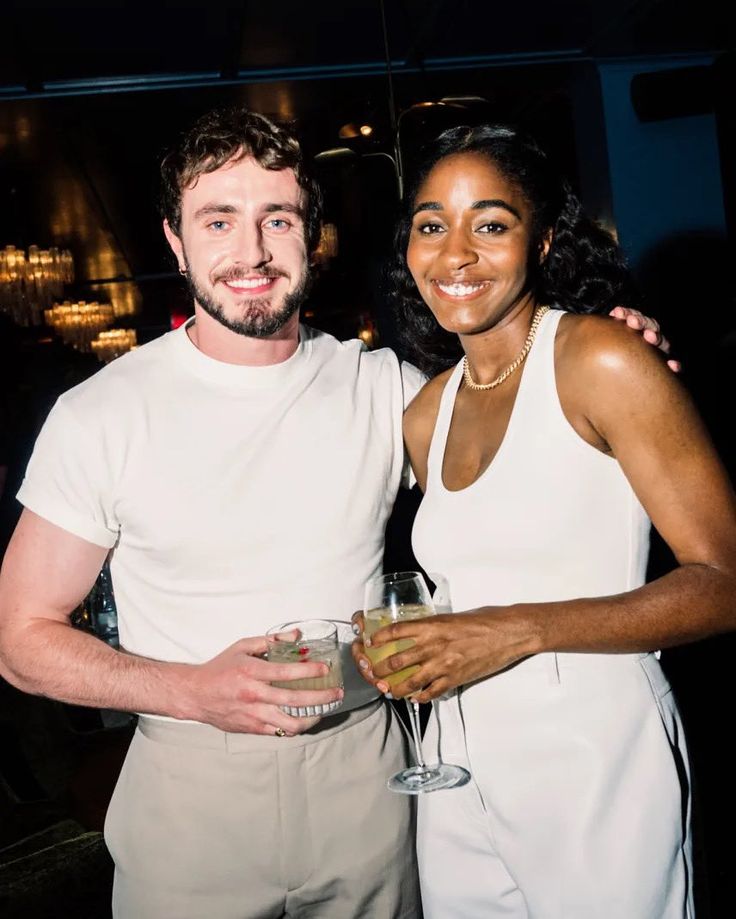 a man and woman standing next to each other holding wine glasses