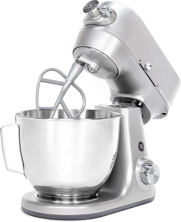 an electric mixer with a metal bowl on it's side and a whisk attachment in the middle