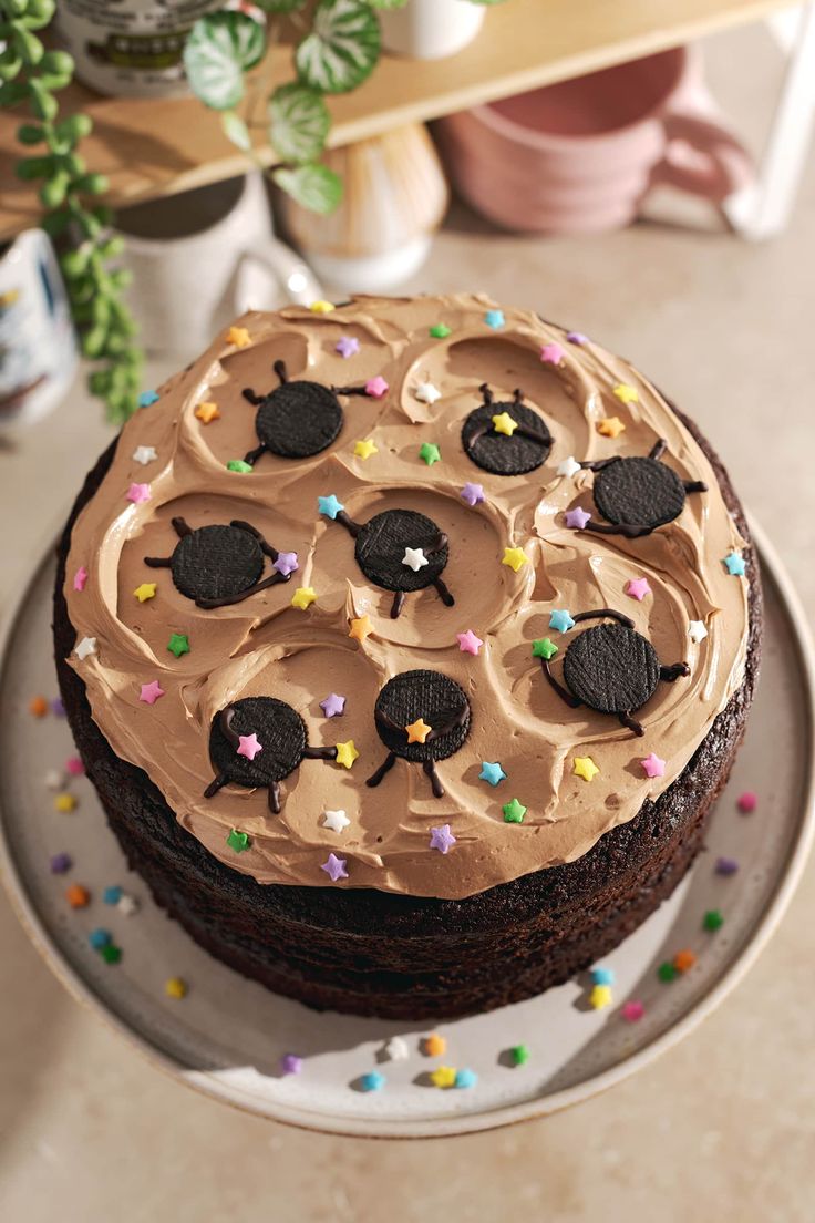 a chocolate cake with frosting and oreo cookies on top sitting on a plate