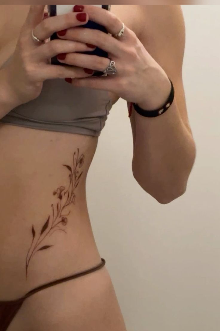 a woman with tattoos on her stomach taking a selfie