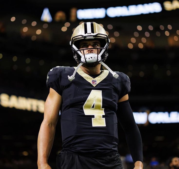 a football player wearing a black uniform with gold numbers on the front and white number four on the back