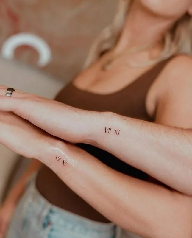 two people with matching tattoos on their arms, one is holding the other's arm