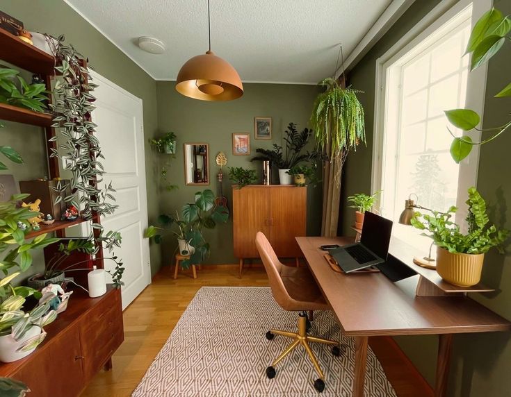 a home office with lots of plants in the corner