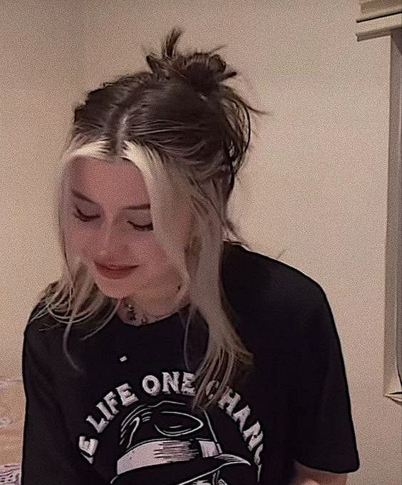 a woman with long hair wearing a black shirt and looking down at her cell phone