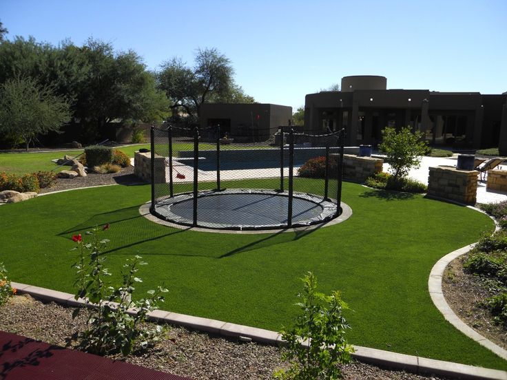 a backyard with artificial grass and a trampoline