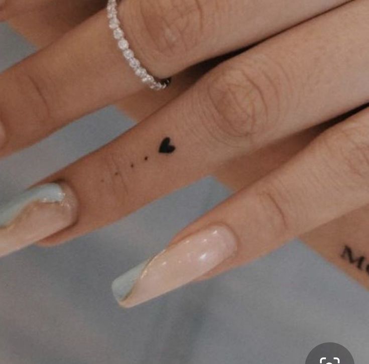 a woman's hand with white and black nail polish on it, holding a diamond ring