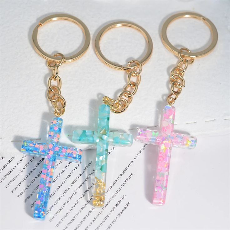 three cross shaped keychains on top of a piece of paper next to each other