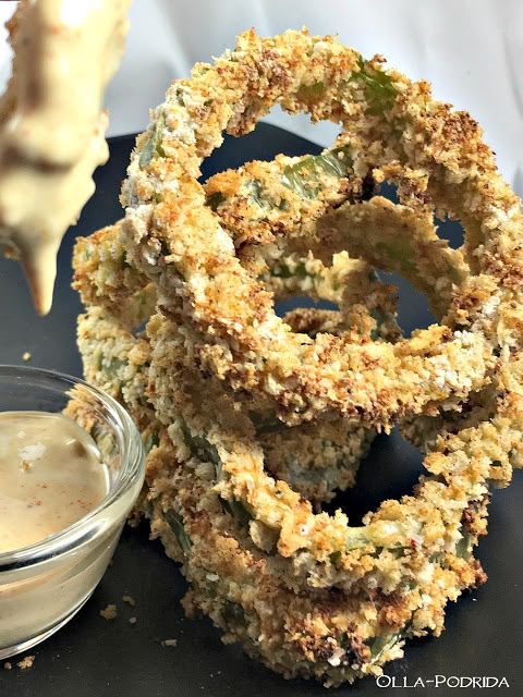 fried onion rings and dipping sauce on a black plate next to garlic breadsticks