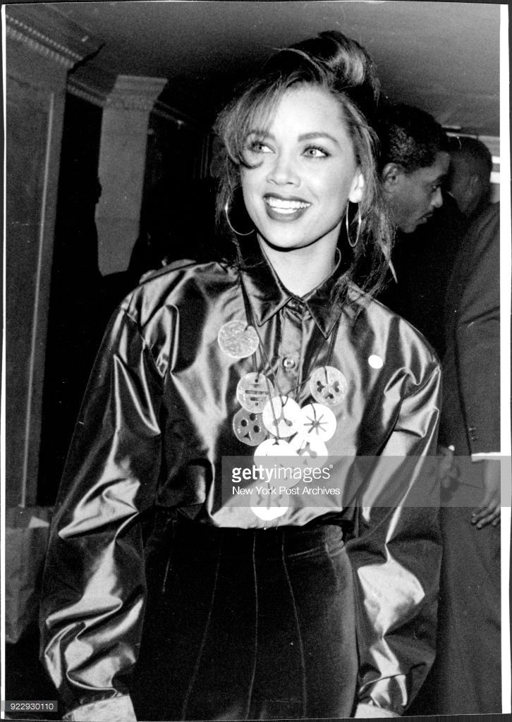 an old photo of a woman wearing a satin shirt and pants with buttons on the collar