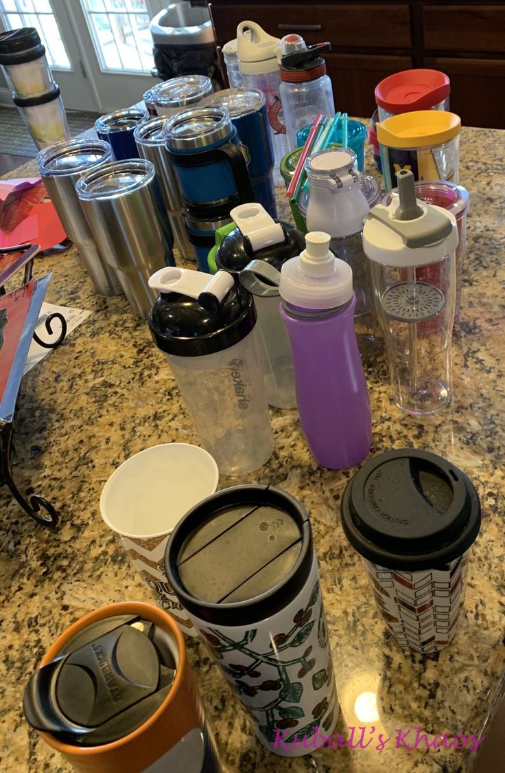 many different cups are sitting on the counter top next to each other and one has a straw in it