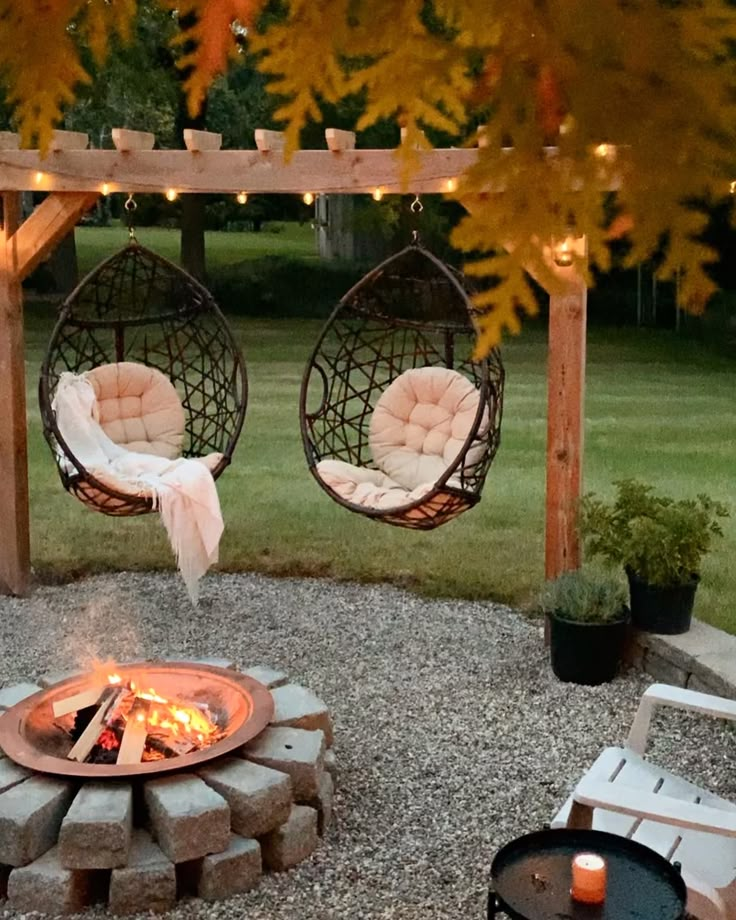 an outdoor fire pit with two hanging chairs