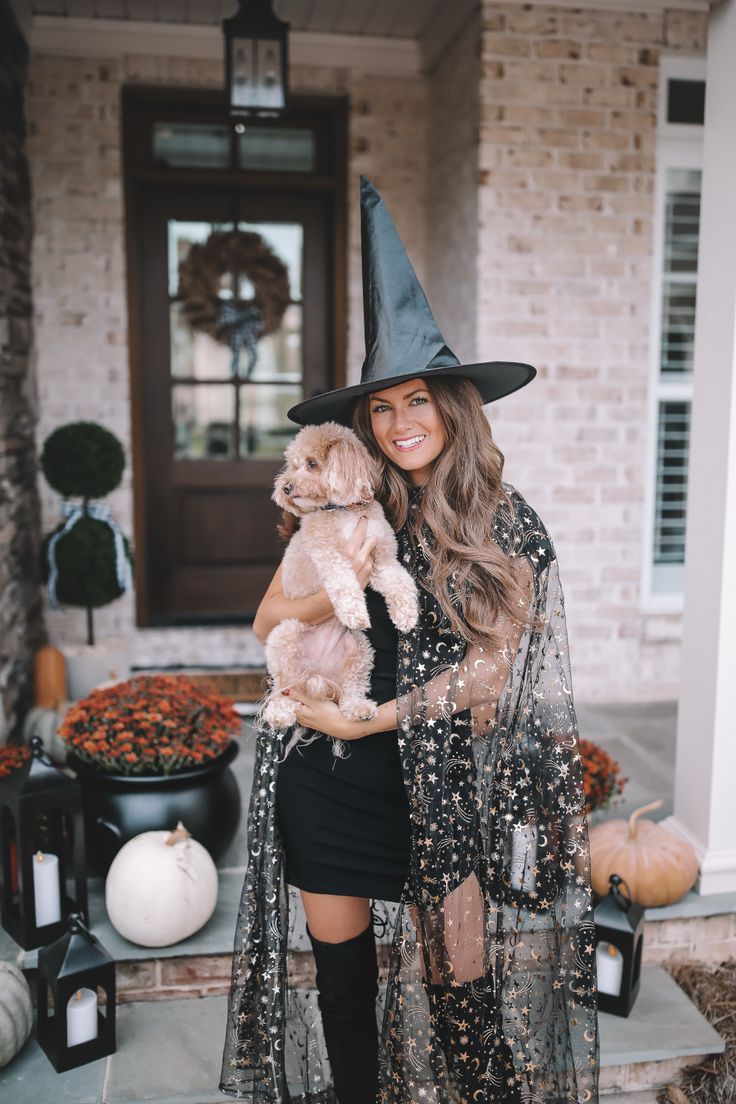 a woman in a witch costume holding a dog