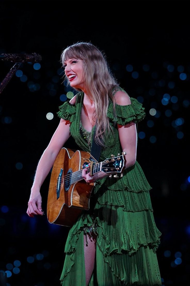 a woman in a green dress holding a guitar