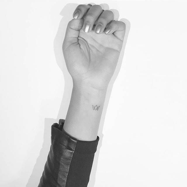 a black and white photo of a woman's arm with a small tattoo on it