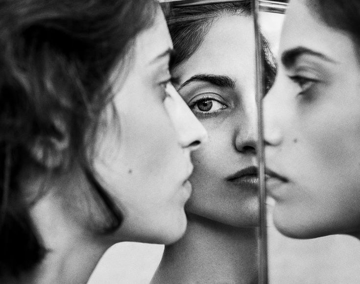 three women are looking in the mirror with their faces close together and one woman has her eyes closed