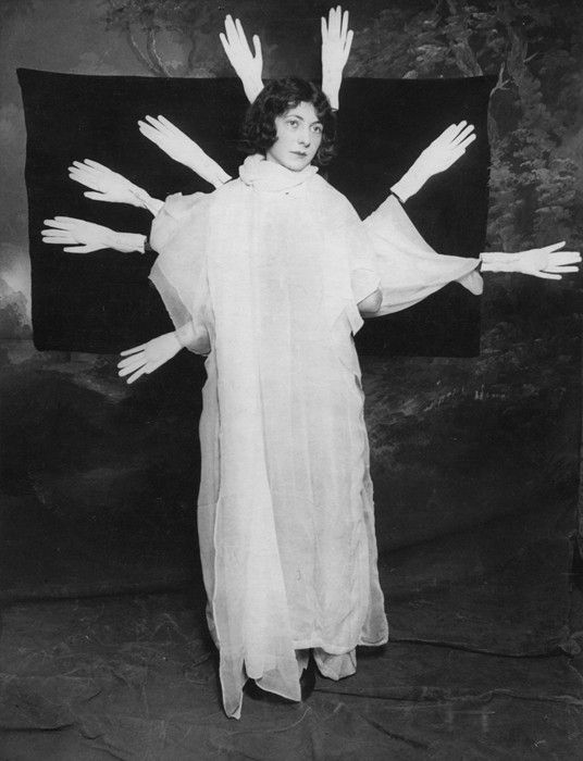 an old photo of a woman with her arms outstretched in front of a black and white background