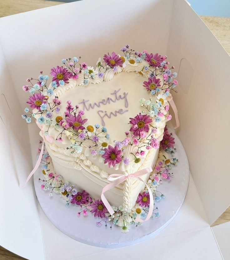 a heart shaped cake in a box with flowers on it