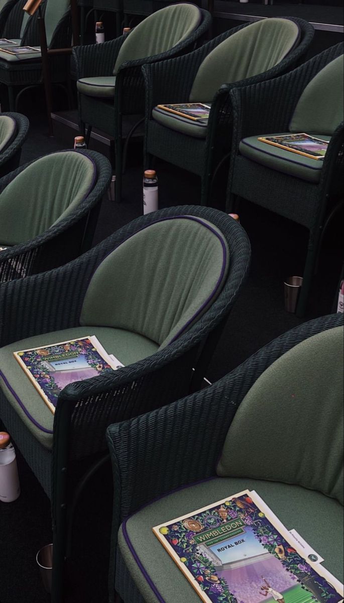 rows of green chairs with pictures on them in an empty theater room, one sitting down and the other standing up