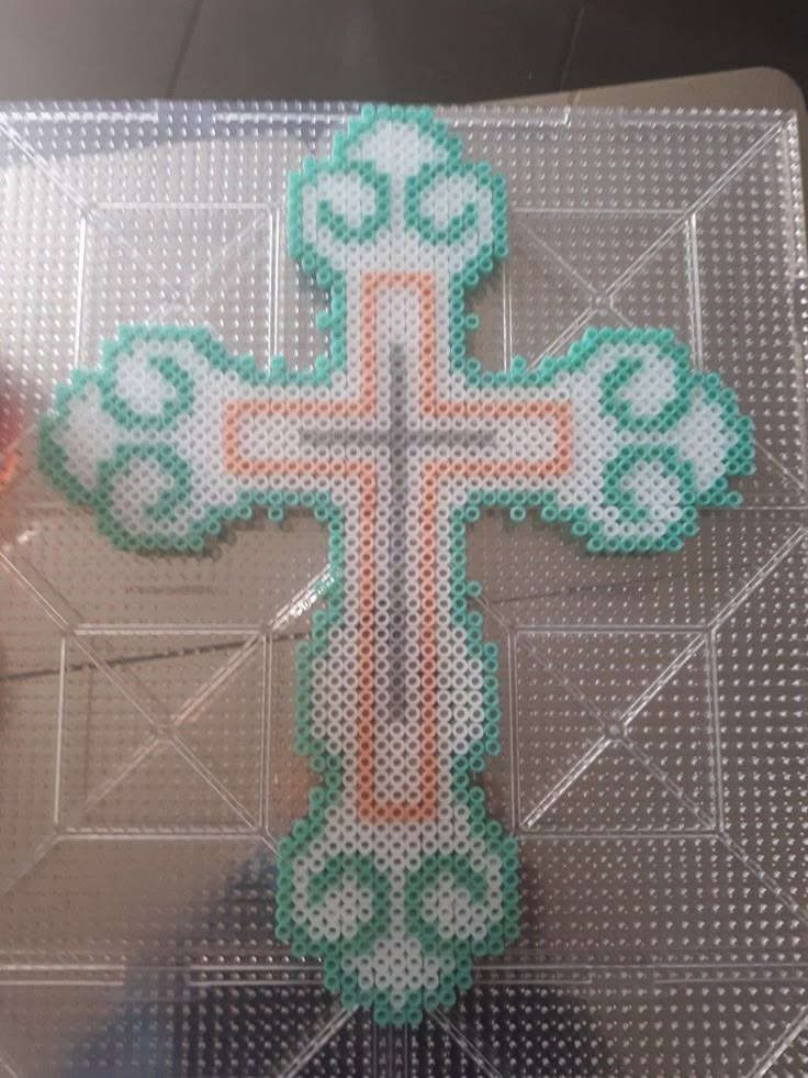 a cross made out of plastic sitting on top of a glass table next to an orange and white object