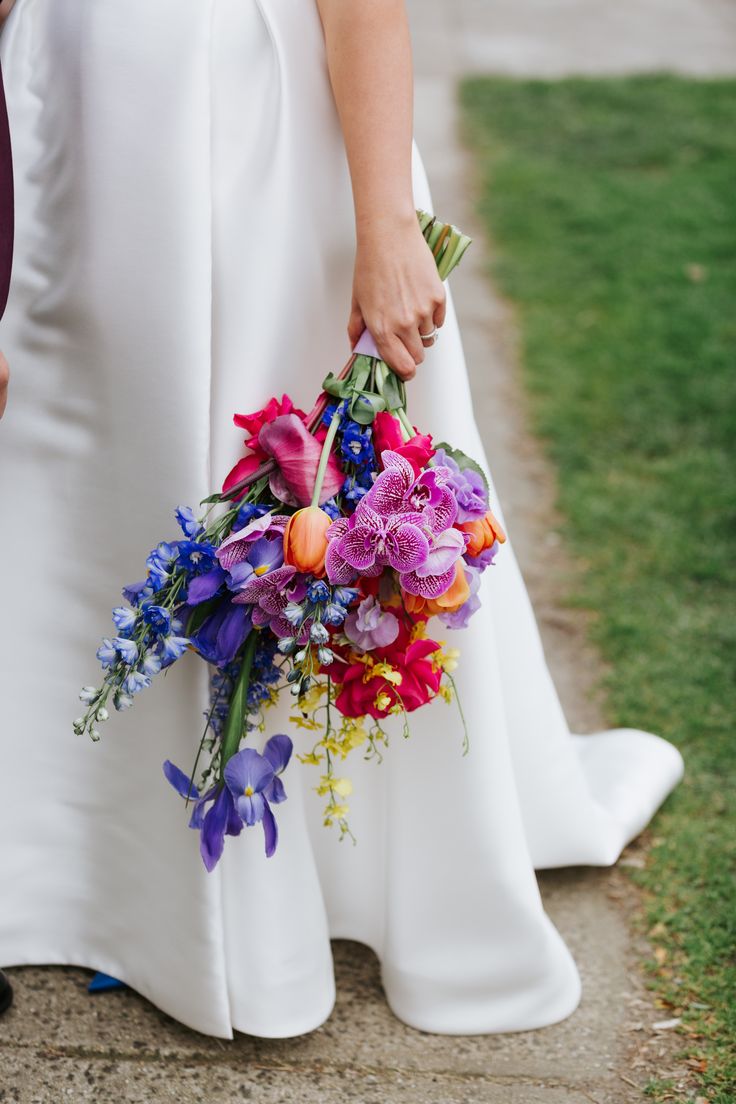 a bride and groom hold their bouquets on the sidewalk in front of some grass