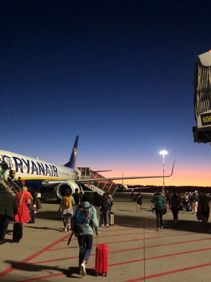 people are walking towards an airplane on the tarmac at sunset or sunrise, as it is about to take off