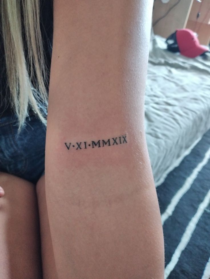 a woman's arm with a roman numeral tattoo on the left side of her arm