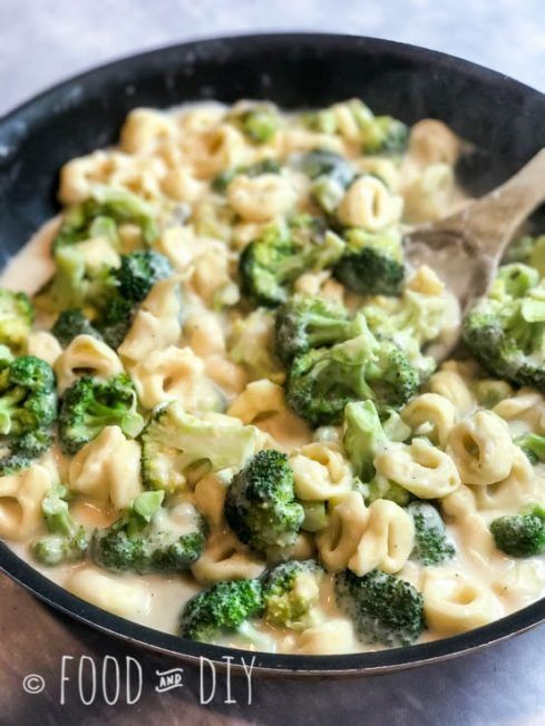 a skillet filled with macaroni and broccoli on top of a table