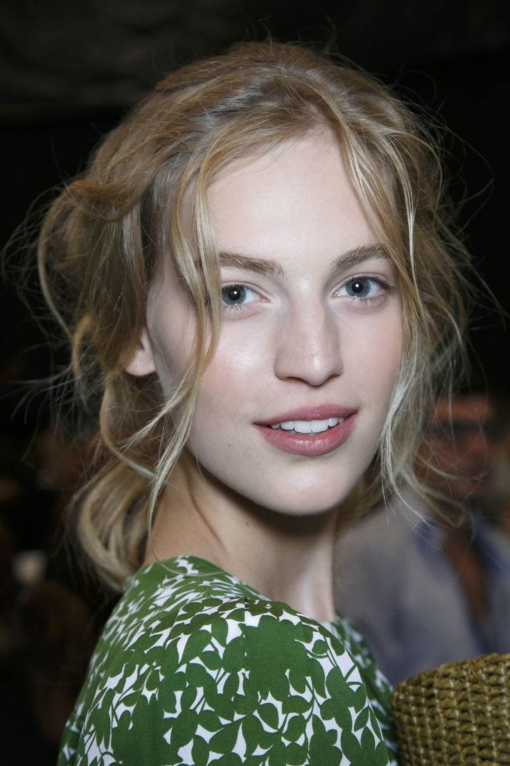 a close up of a person wearing a green and white dress with wavy hair, smiling at the camera