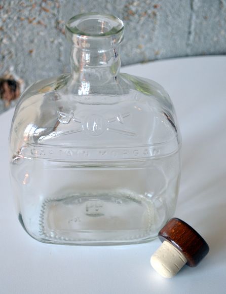 a glass bottle sitting on top of a white table next to a wooden stopper